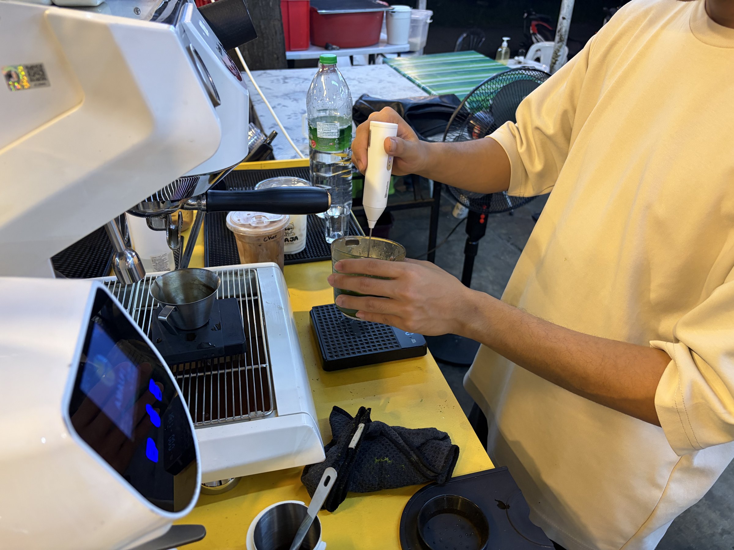 Barista frothing milk behind the espresso machine